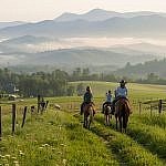 A family enjoys beginner horseback riding for the first time in Sandy Mush Valley, just northwest of Asheville in the Blue Ridge Mountains.
