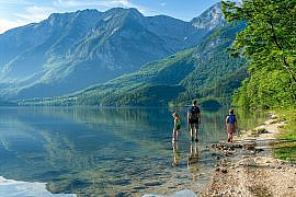Family walking along Lake Bohinj in the Julian Alps Slovenia with kids enjoying an alpine outdoor adventure