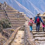 Family viewing Machu Picchu with kids from a trail overlooking the Inca citadel and Huayna Picchu in Peru.