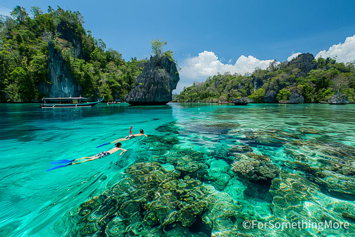Family snorkeling among the limestone islands of Raja Ampat, Indonesia, on a remote family water adventure.
