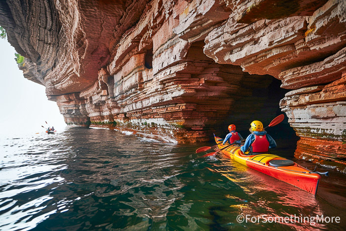 Family kayaking the Apostle Islands sea caves on Lake Superior during an outdoor family adventure trip.
