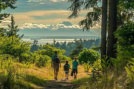 Family hiking in Discovery Park with Puget Sound and the Olympic Mountains during a Seattle with kids trip.