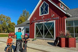 Family with two young boys and mountain bikes outside the Fort Ransom State Park Visitor Center in North Dakota’s Sheyenne River Valley during fall.