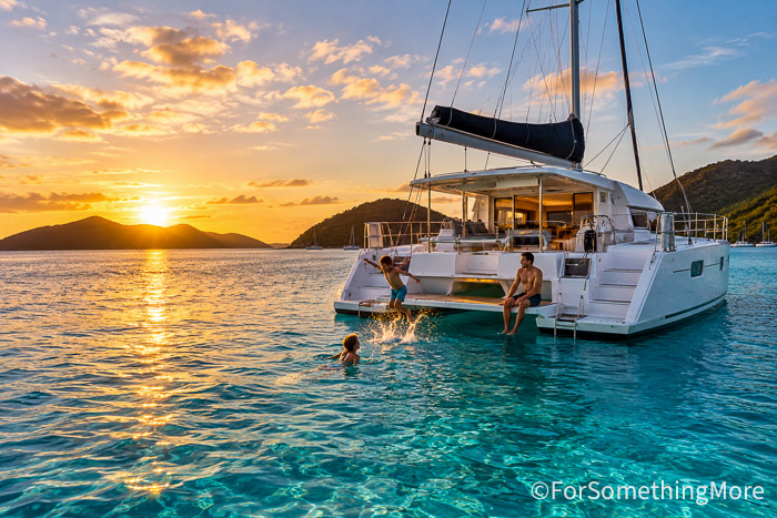 Children swimming from a catamaran during a family sailing and snorkeling adventure.