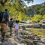 Alt text: Parent and two children hiking beside a creek during a Texas Hill Country with kids adventure near Austin.