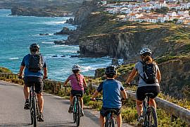 Family cycling along a scenic Portuguese coastline during a Portugal cycling holiday.
